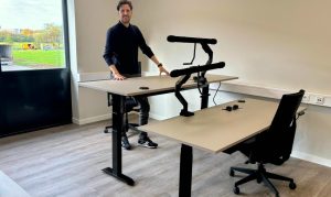 Medewerker wisselt tussen zitten en staan aan een zit-sta bureau voor een gezonde werkhouding.